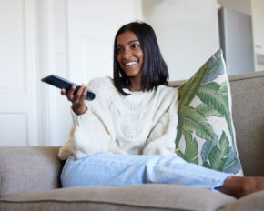 Shot of a beautiful young woman holding a remote control while sitting on the couch at home.